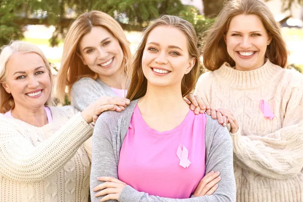 Smukke kvinder i forskellige aldre med lyserøde bånd udendørs. Brystkræft koncept - Stock-foto