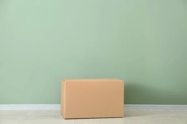 Caja de cartón cerca de la pared de color — Foto de Stock