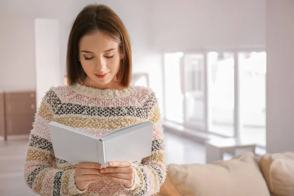 Beautiful young woman reading book at home — Stock Photo, Image