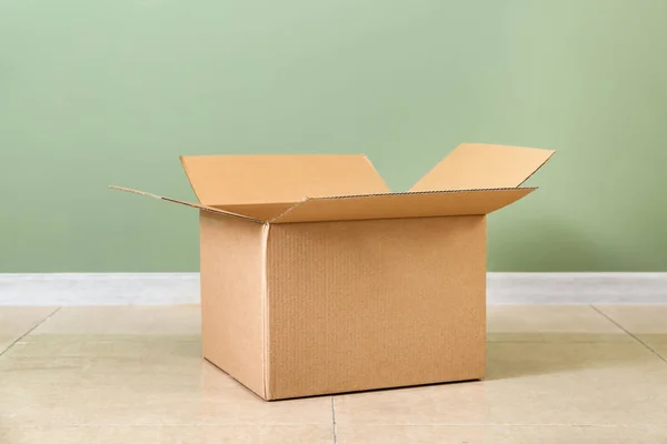 Cardboard box near color wall — Stock Photo, Image