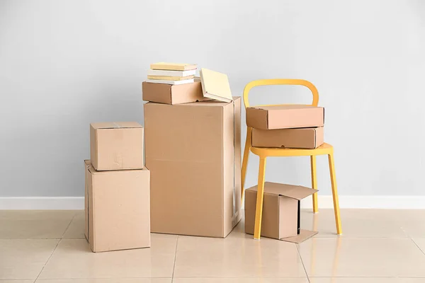 Boîtes en carton avec effets personnels prêtes à emménager dans une nouvelle maison près d'un mur léger — Photo