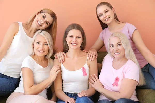 Hermosas mujeres de diferentes edades con cintas de color rosa sobre fondo de color. Concepto de cáncer de mama — Foto de Stock