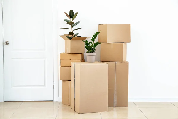 Boîtes en carton avec effets personnels prêtes à emménager dans une nouvelle maison près d'un mur blanc — Photo