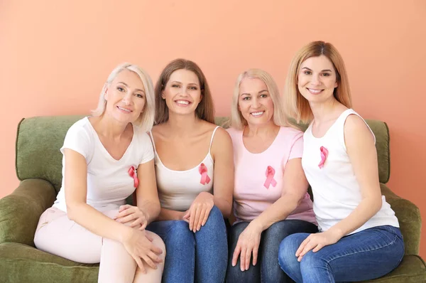 Mooie vrouwen van verschillende leeftijden met roze linten op kleur achtergrond. Borst kanker concept — Stockfoto