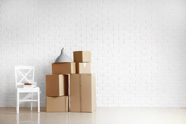 Beyaz tuğla duvar ayakın yeni eve taşımak için hazırlanan eşyalarını ile karton kutular — Stok fotoğraf