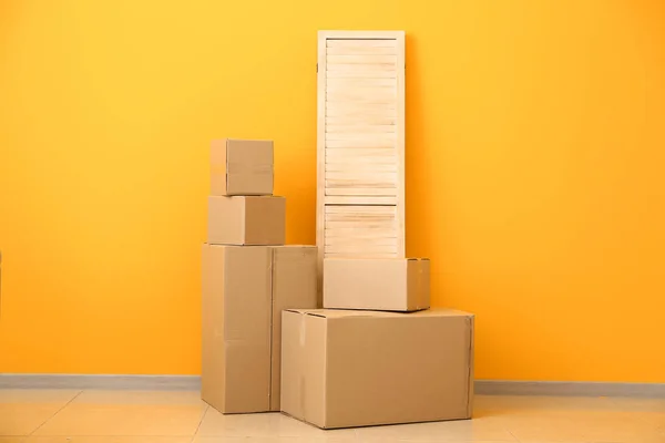Cardboard boxes with belongings prepared for moving into new house near color wall — Stock Photo, Image