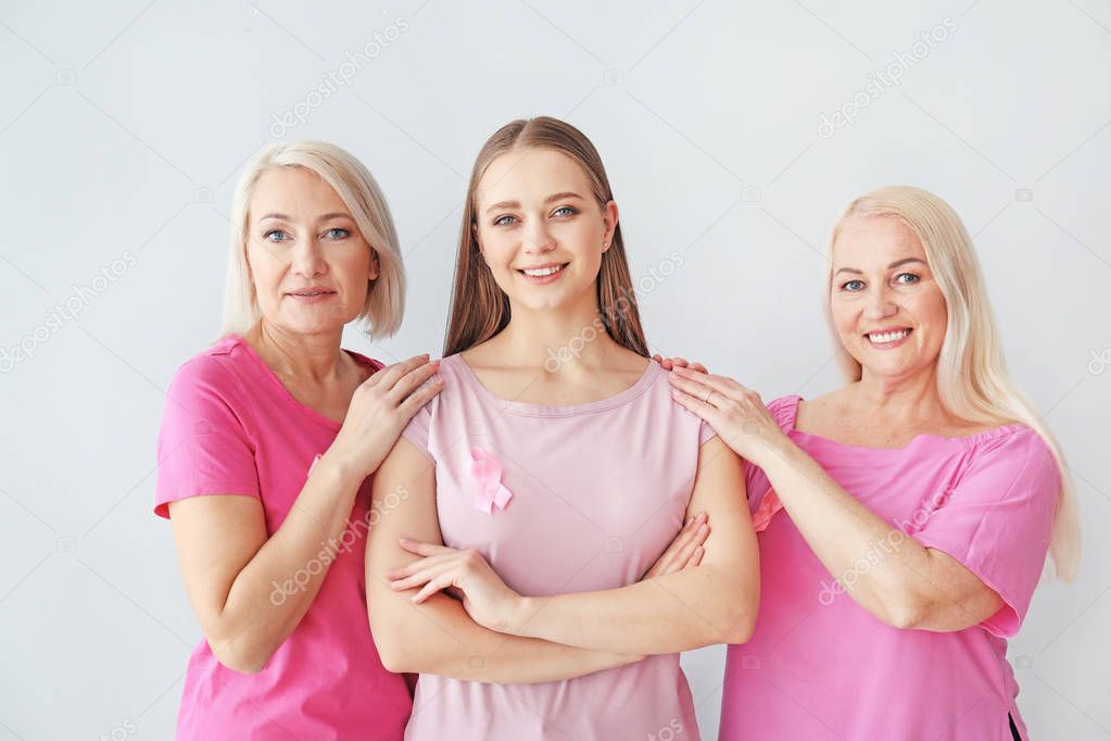 Beautiful women of different ages with pink ribbons on light background. Breast cancer concept