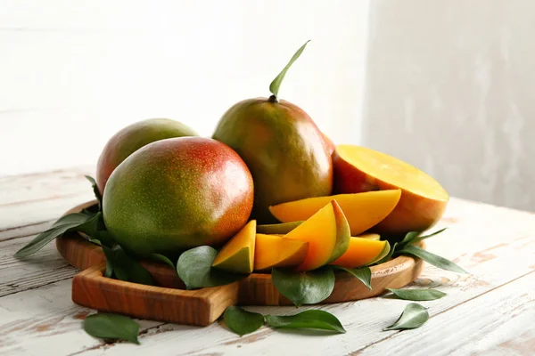Board with tasty fresh mango on wooden table — Stock Photo, Image