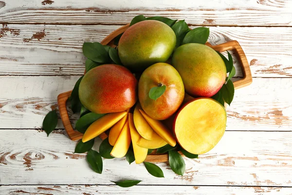 Deska z smacznym świeżym mango na drewnianym stole — Zdjęcie stockowe
