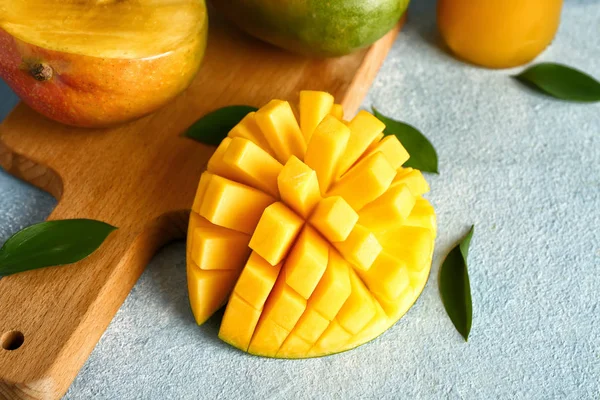 Tasty fresh mango with board on color background — Stock Photo, Image