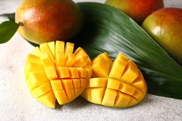 Вкусное сладкое манго с тропическим листом на сером фоне — стоковое фото