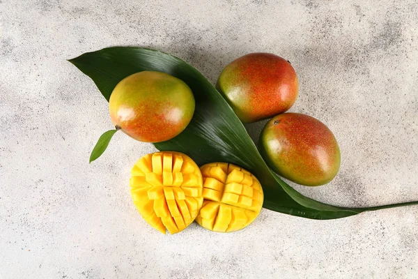 Tasty sweet mango with tropical leaf on grey background — Stock Photo, Image