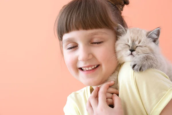 Flicka med söt fluffiga kattunge på färg bakgrund — Stockfoto