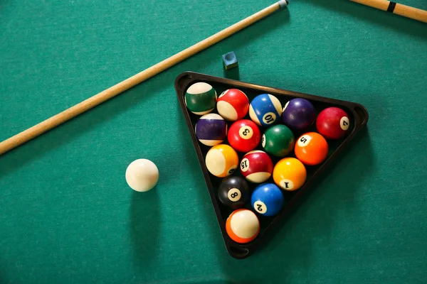 Billiard balls in triangle rack with cues on table — Stock Photo, Image