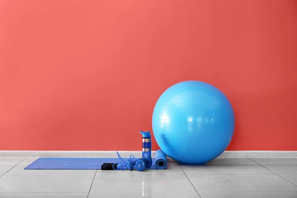 Set de equipamiento deportivo con pelota fitness y botella de agua cerca de la pared de color — Foto de Stock