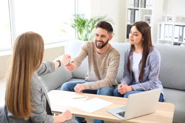 Emlakçı genç çift için yeni evden bir anahtar veren
