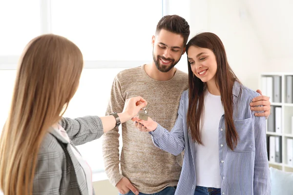 Inmobiliaria dando las llaves de la casa nueva a la pareja joven — Foto de Stock