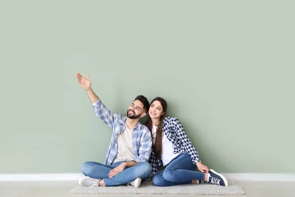 Pareja joven sentada cerca de pared de color — Foto de Stock