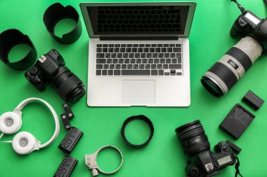 Modern equipment of professional photographer with laptop on color background clipart