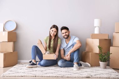 Yeni evlerinde ışık duvarının yanında oturan eşyaları ve kedi yavrusu ile genç çift