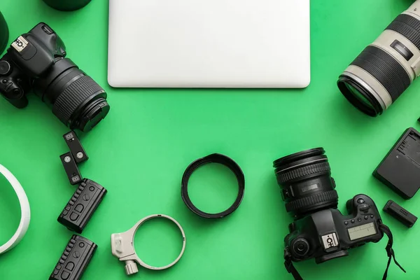 Equipamento moderno de fotógrafo profissional com laptop sobre fundo de cor — Fotografia de Stock