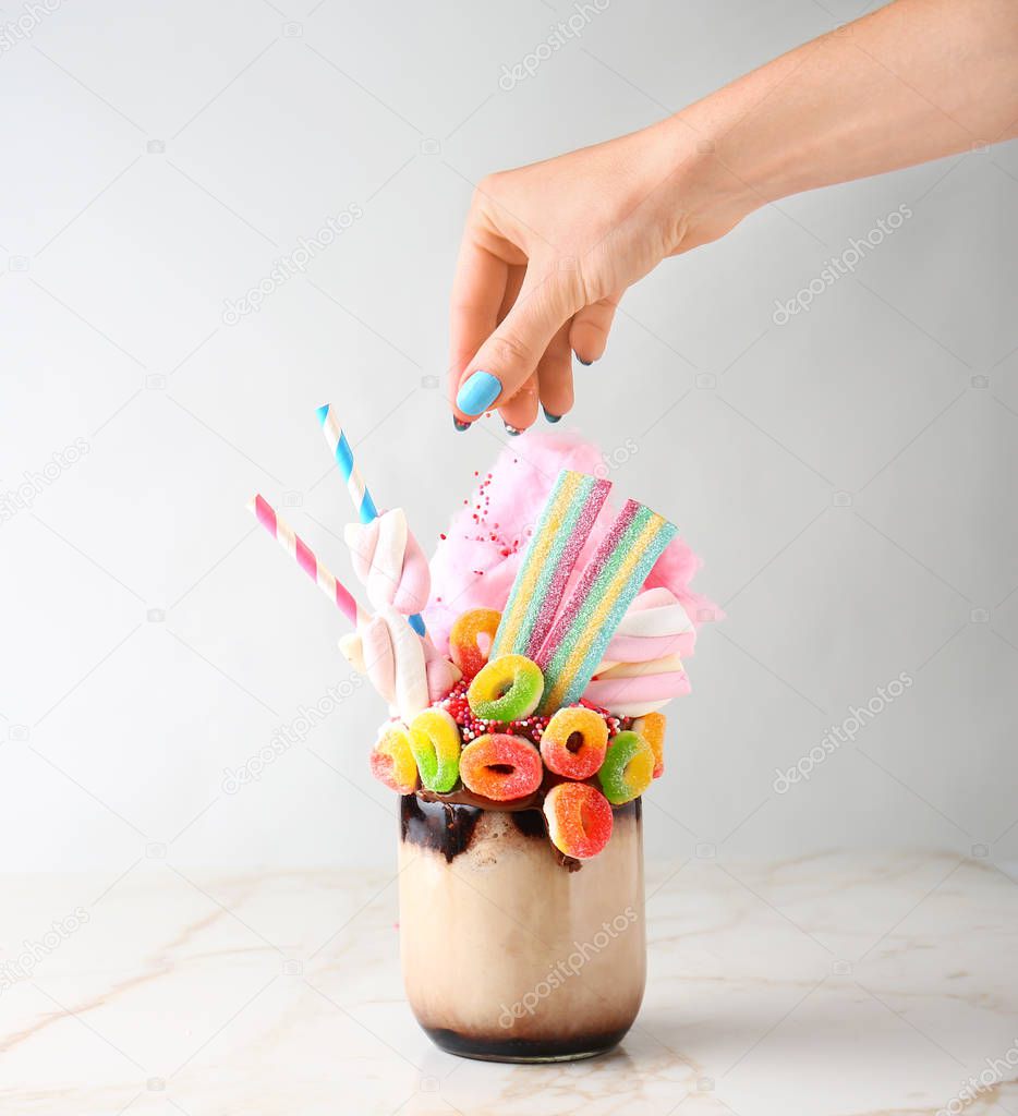 Woman decorating delicious freak shake on table