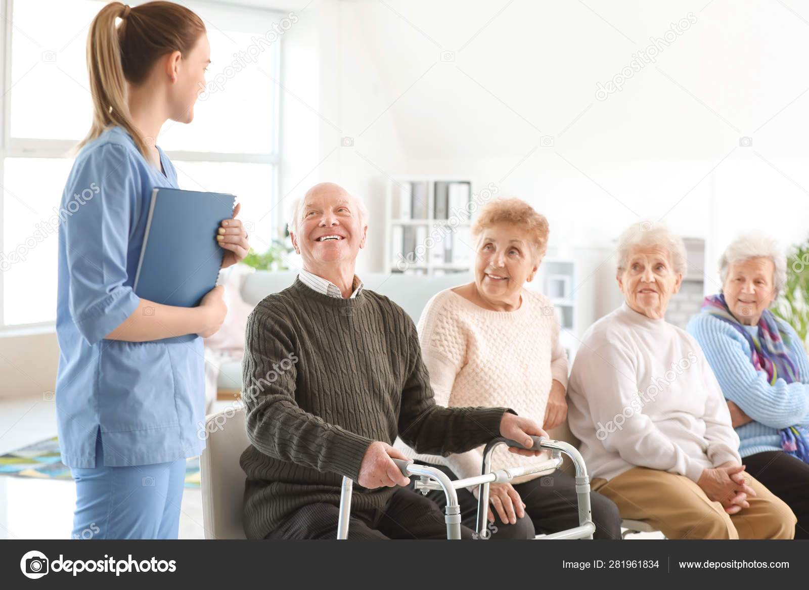 Young caregiver with group of senior people in nursing home Stock Photo