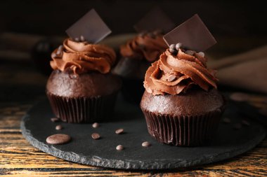 Ahşap masa üzerinde lezzetli çikolata cupcakes ile kayrak plaka