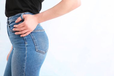 Açık arka planda şık kot pantolon giyen genç kadın