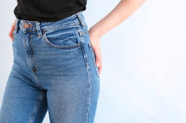 Young woman wearing stylish jeans pants on light background clipart