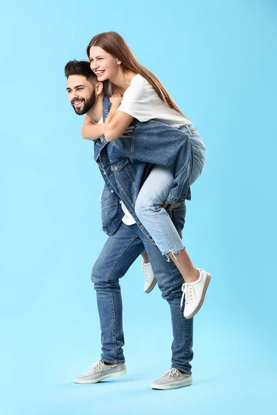 Elegante jovem casal em jeans roupas em fundo de cor — Fotografia de Stock