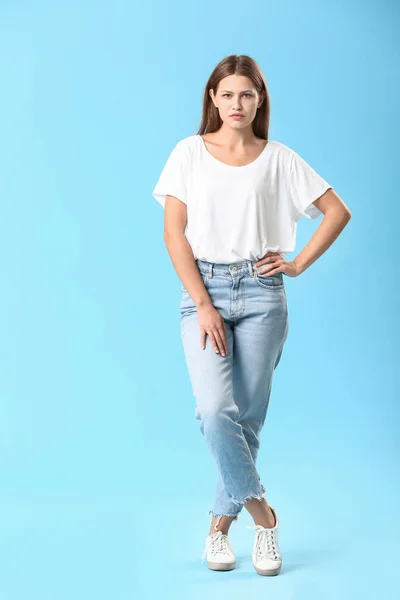 Stylová mladá žena v džínách na barevném pozadí — Stock fotografie