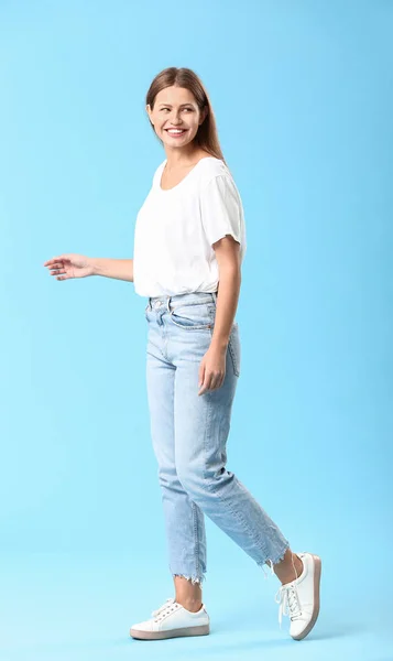 Стильна молода жінка в джинсах на кольоровому фоні — стокове фото