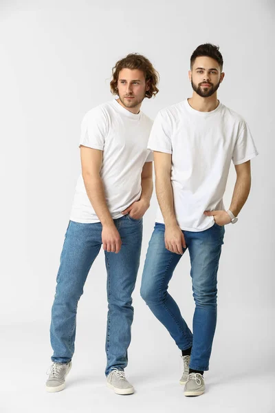 Snygga unga män i jeans på vit bakgrund — Stockfoto