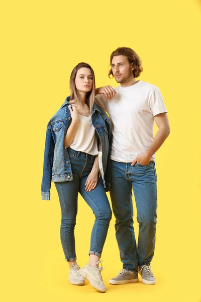 Elegante pareja joven en jeans sobre fondo de color — Foto de Stock