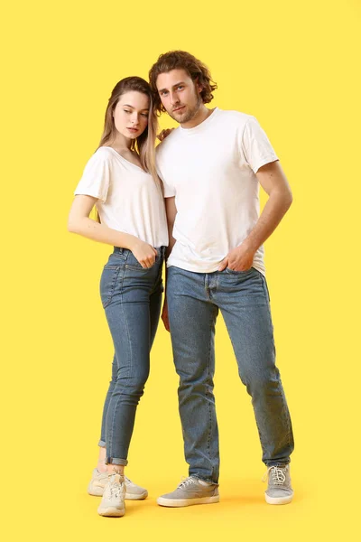 Elegante pareja joven en jeans sobre fondo de color — Foto de Stock