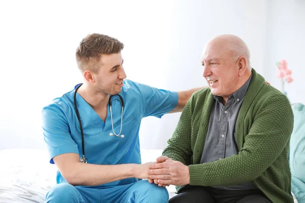 Medical worker with senior man in nursing home
