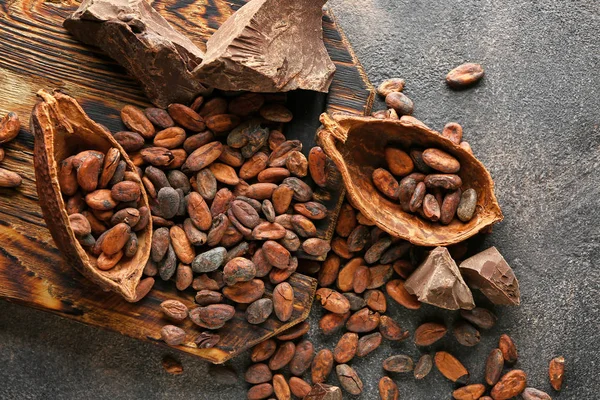 Kakaobohnen, Schoten und Schokolade auf Grunge-Hintergrund — Stockfoto