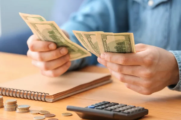 Woman counting money at table, closeup