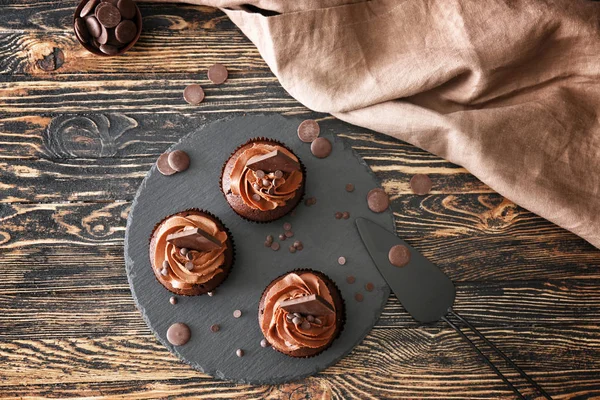 Břidlicová deska s chutnými čokoládovými koláčky na dřevěném stole — Stock fotografie
