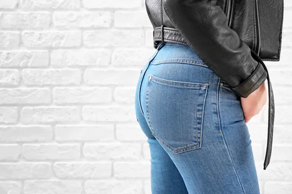 Jonge vrouw dragen stijlvolle jeans broek op witte bakstenen achtergrond — Stockfoto