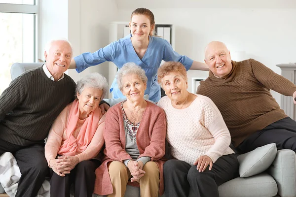 Młody opiekun z grupą osób starszych w domu opieki — Zdjęcie stockowe