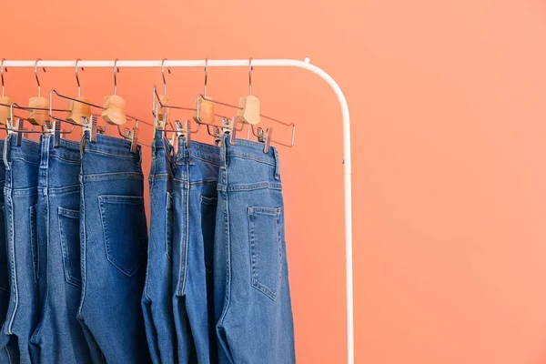 Perchero con pantalones vaqueros elegantes sobre fondo de color — Foto de Stock