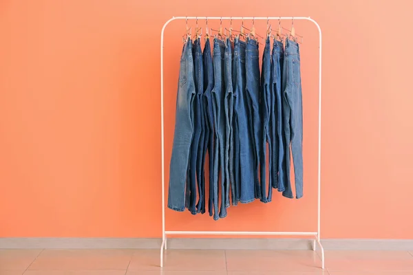 Kleding rek met stijlvolle jeans broek in de buurt van kleur muur — Stockfoto