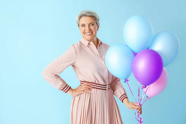 Volwassen vrouw met lucht ballonnen op kleur achtergrond — Stockfoto