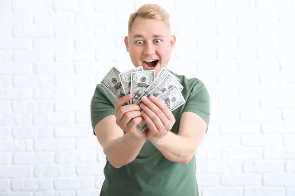 Joyeux jeune homme avec des billets en dollars sur fond de brique blanche — Photo
