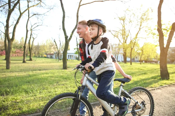 Padre enseñando a su hijo a andar en bicicleta al aire libre — Foto de Stock