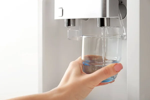 Женщина наливает воду из холодильника в стекло — стоковое фото