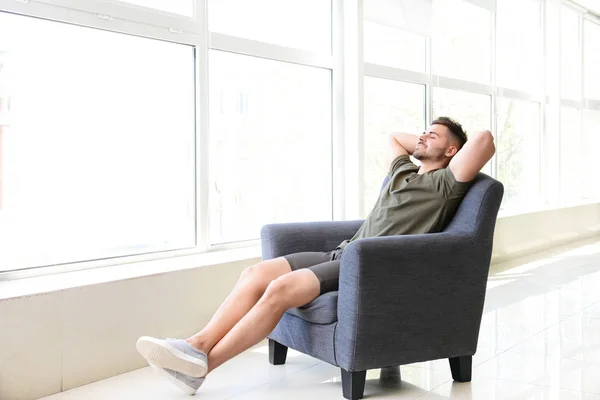 Bonito homem descansando em poltrona em casa — Fotografia de Stock