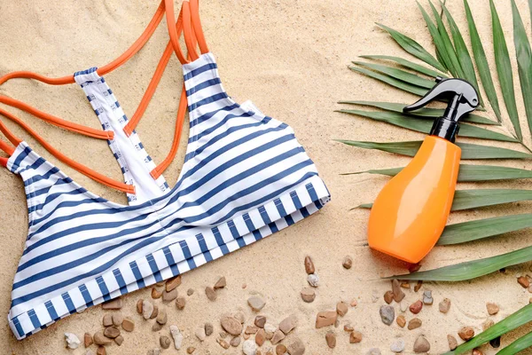 Bouteille de crème solaire et maillot de bain femme sur sable — Photo